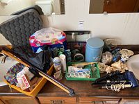 Overview of bathroom accessories lot showing walking sticks, first aid, foot care, decor and hair care items on a wooden surface.