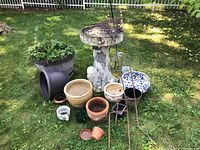 Overall view of lot showing wooden barrel planter, ceramic/clay pots, bird bath, shepherd hooks on grass outdoors