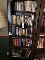 Bookshelves holding multiple books with varied titles, mainly nonfiction and reference books, including large volumes and smaller paperbacks.