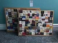 Photo of two large wooden framed display cases filled with organized matchbooks from various global businesses.