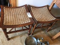 Pair of Indonesian style wooden benches with woven lace seats placed side by side on carpeted floor.