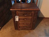 Front view of carved wooden jewelry box showing 4 drawers with heart-shaped handles and carved detail.
