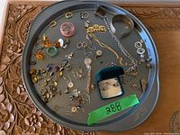 Overview of all jewelry on tray including necklaces, earrings, pins, cuff bracelet.