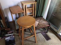 Four stools and a small wood folding table shown next to each other inside a room with carpet flooring.