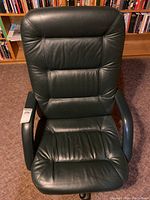 Front view of dark green leather office chair showing padded backrest and seat, with armrests.