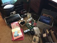 Overview of the lot showing shredder, HP Deskjet printer, phones, briefcases, folders, and miscellaneous office supplies on a floor