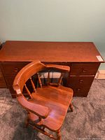 Photo of wooden double pedestal desk with closed drawers and pine barrel wood chair in front