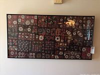 Full view of the framed textile art on the wall, showing its size and overall appearance.