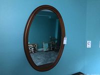 Full view of oval maple wall mirror hanging, showing its size and shape.