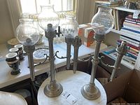 Set of 2 antique nickel plated brass spring-loaded candle lamps with multiple candle holders and glass globes. Four globes present in total, 2 globes missing.