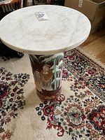 Full view of the side table showing white marble top and umbrella stand base on oriental rug.