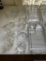 Collection of various glass and crystal entertaining pieces including small bowls, cups with handles, and dessert plates.