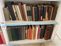 Shelf with two rows of vintage books including dictionaries, encyclopedias, and grammar books in hardcover and clothbound editions.