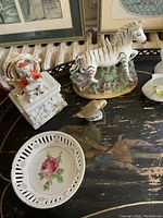 Close-up of Staffordshire zebra figurine and nearby porcelain goose on table.