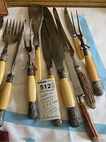 Full view of fish forks and cutters with cream-colored ornate silver plated handles and stainless steel blades/prongs