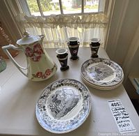 Photo showing three black and white French Montereau dinner plates with floral border, vintage water pitcher with floral design, and three black and gold vases.