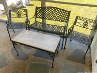 Full set showing bench, coffee table, and two chairs on stone floor of covered porch under natural light.