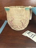 Close-up of the cream ceramic pitcher showing coral and shell texture with turquoise accents.