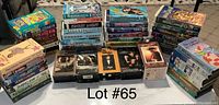 Photo showing the entire lot of approximately 48 kids VHS tapes stacked in piles, various titles visible with colorful covers.
