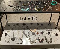 Overview of 33 sets of necklaces and matching pierced earrings laid out on two tables, variety of styles and colors visible.