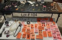 Tabletop view of necklaces and earrings arranged on cards, bracelets visible, showing variety and quantity