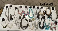 Full lot display showing 20 necklaces and 20 matching earrings on black and white holders laid out on white surface.