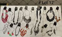 Photo showing 15 necklaces laid out in a row along with 15 matching pairs of earrings, various styles and colors.