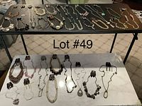 Full overview of 30 necklaces and matching 30 pairs of earrings arranged on tables.