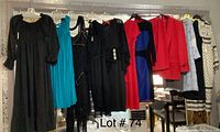 Wide view of women's dresses and suit hanging on a rod showing variety of colors and styles