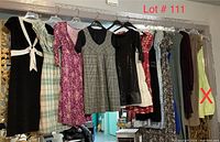 Nine women's dresses hanging on a rack in a living space, photographed from front view showing details.