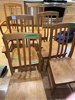 Photo showing 6 wooden dining chairs, 2 with armrests and 4 straight back chairs arranged in kitchen setting.