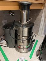 Full view of Breville Juice Fountain Elite juicer showing its stainless steel body, black components, chute, cord and power button on front.