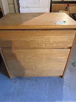 Front view of rectangular light wood cabinet with one drawer and a larger front panel door below it, showing scratches and water marks.