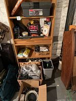 Wide view showing shelving with toolbox, power pack, boxed items and baskets with cords and tools.