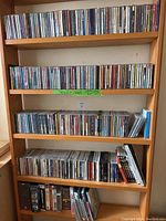 Shelf filled with rows of CDs and DVDs stacked tight in jewel and standard cases of varying colors and labels.