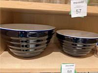 Photo of two ceramic mixing bowls, large and small, black with white interiors, with horizontal ridged design on exteriors.