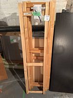Photo of stacked wooden side frames with cross supports leaning against a wall in basement.