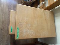 Top view of larger nesting table with visible circular stains and scratches on light wood surface
