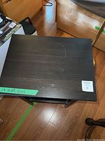 Top view of black night stand showing scratches and green tape with measurements.