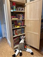 Photo of a wooden cabinet with shelves containing multiple puzzles and a llama costume lying on the floor in front.