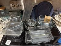 Overview of multiple clear glass Pyrex baking dishes and bowls arranged on stovetop.