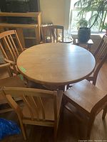 Overhead photo of the round solid oak dining table surrounded by wooden chairs, showing the table top and part of the room.