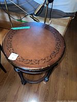 Top view of round wood side table with decorative edge pattern and worn surface.