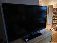 Samsung flat-screen TV on a wooden dresser with visible Samsung logo and MaxSold tag.