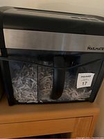 Front view of Mail Mate shredder showing black and silver design and shredded paper in the transparent bin.