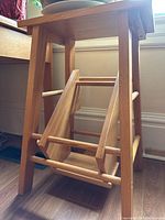 Wooden fold-down step stool showing overall structure and the fold-down steps mechanism with one step missing.