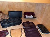 Photo showing various wallets, coin pouches, and eyeglass cases displayed on a wooden surface