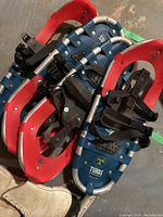 Pair of red and blue metal frame Tubbs snowshoes with adjustable bindings shown stacked