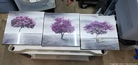 Front view of all three canvas tree artworks arranged side by side on white table