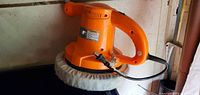 Side view of the orange Chicago auto polisher showing the power cord and wool buffing pad.